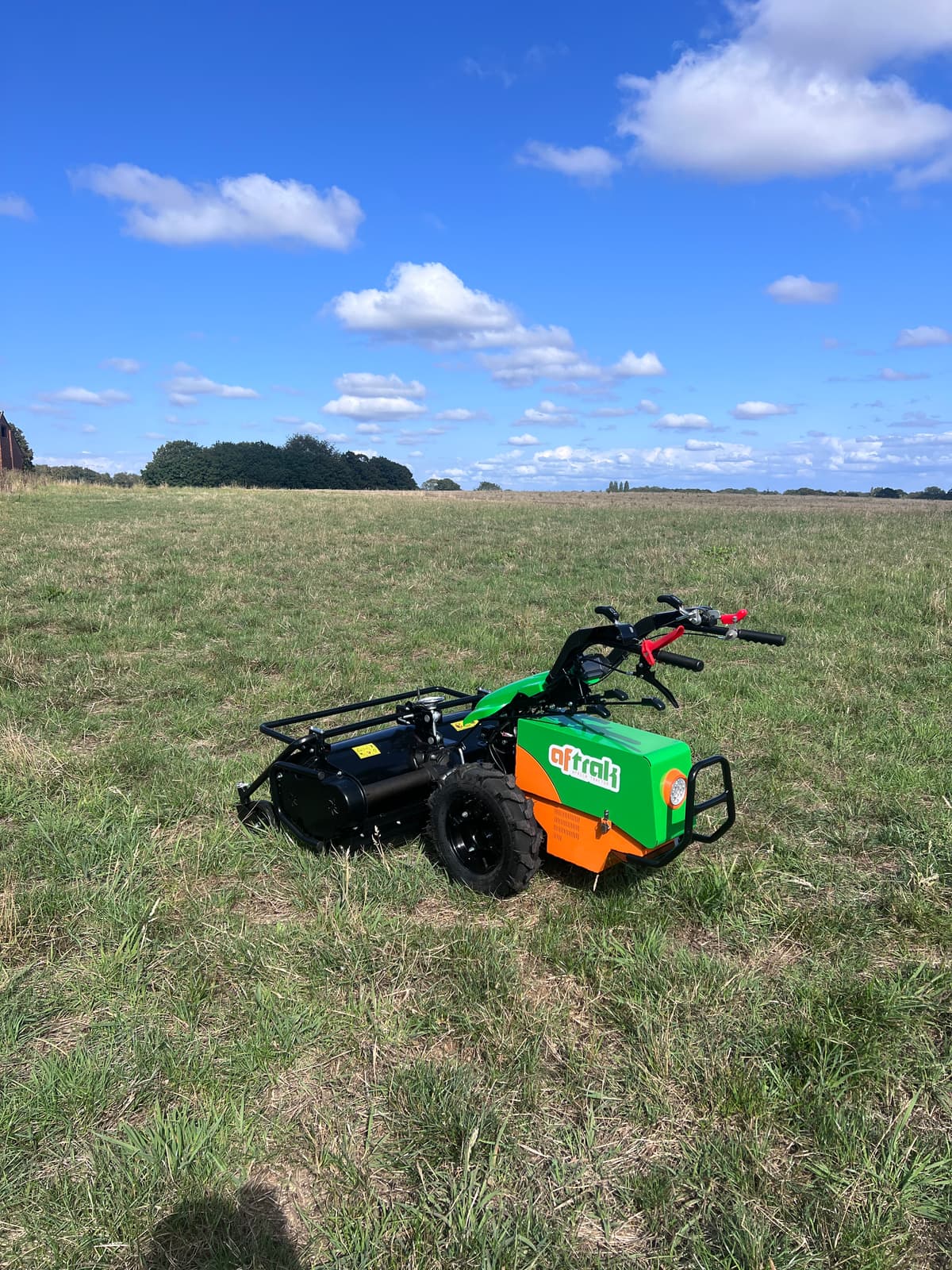 The Aftrak tractor with the flail mower fitted, standing in a mown field under a summer sky