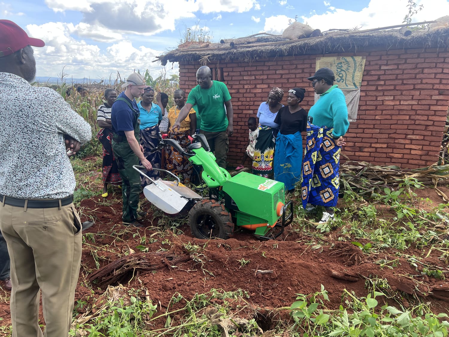 Farmers gathered around the Aftrak tractor on broken red ground at Mzamo, an Aftrak engineer at the handlebars and a trainer talking the group through the machine