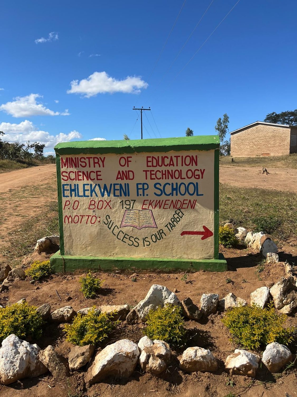 Painted school sign reading Ministry of Education Science and Technology, Ehlekweni F.P. School, Ekwendeni