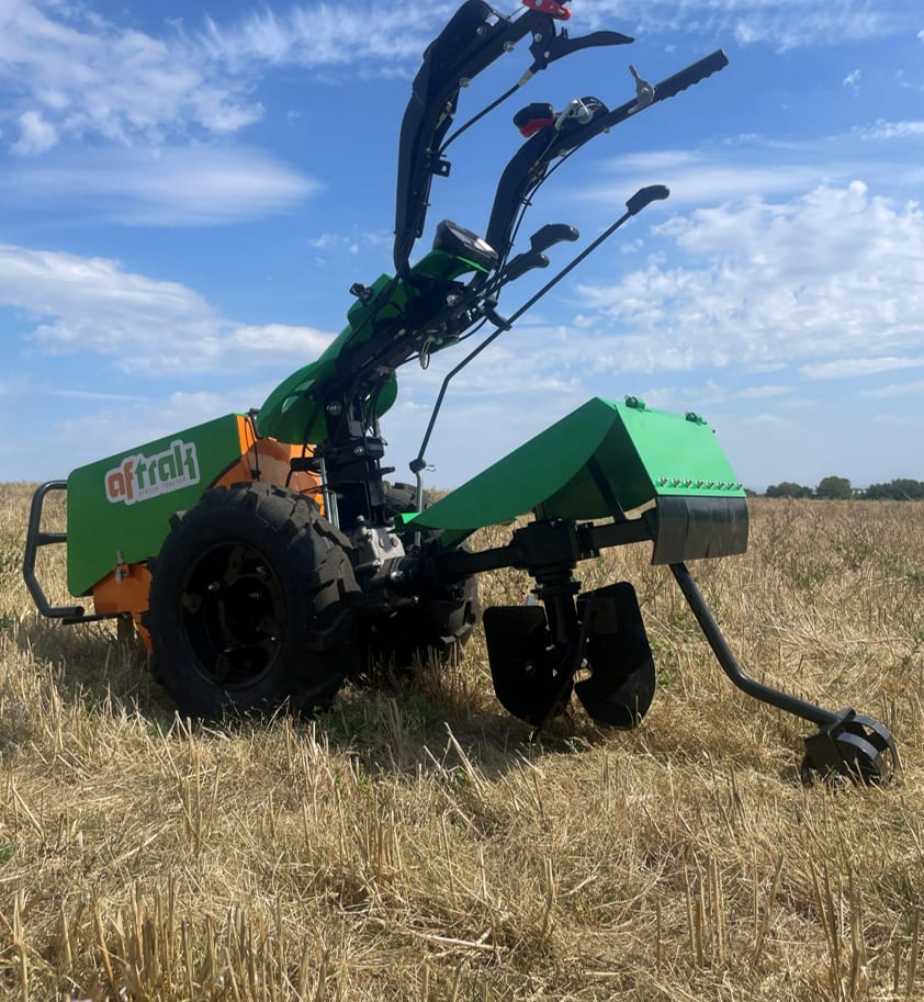 An Aftrak tractor with the rotary plough fitted, standing in cut stubble under a blue sky